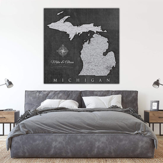 a bedroom with a gray bed and a black and white map of michigan