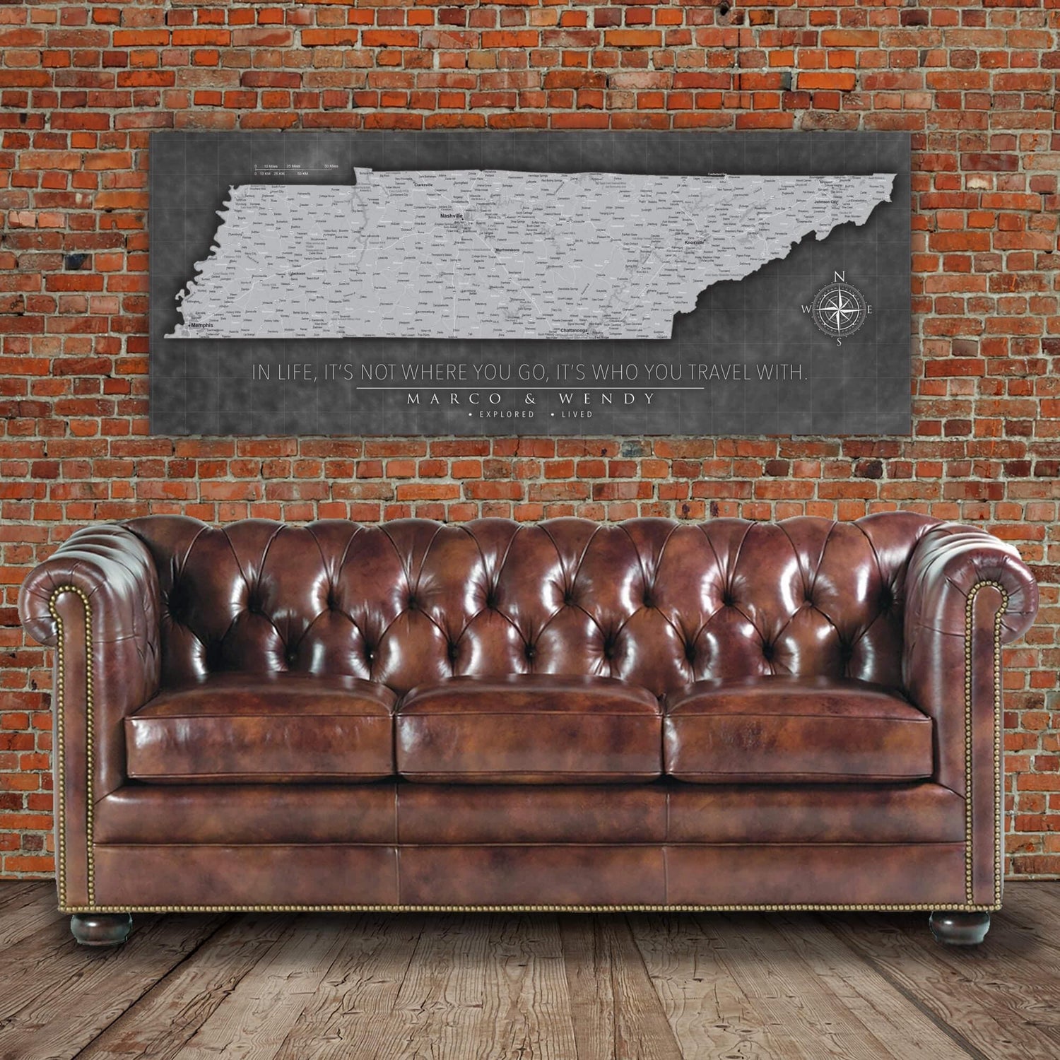 a brown leather couch sitting in front of a brick wall